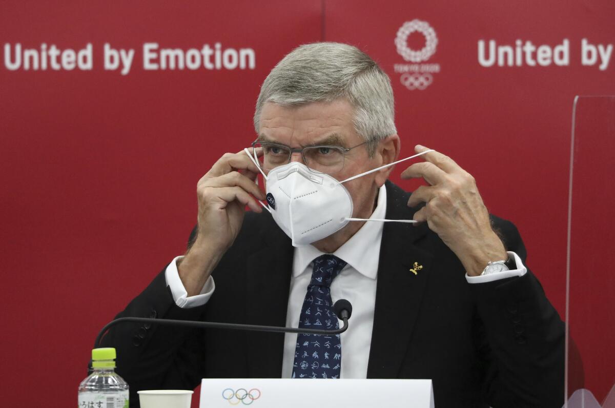 Thomas Bach, International Olympic Committee (IOC) President, puts on his mask before speaking during the joint press conference between IOC and Tokyo Organizing Committee of the Olympic and Paralympic Games (Tokyo 2020) in Tokyo, Japan, Nov. 16, 2020. Olympic participants and fans arriving for next year's postponed Tokyo Olympics are likely to face requirements to be vaccinated to protect the Japanese public, Bach said Monday after meeting with new Prime Minister Yoshihide Suga. (Du Xiaoyi/Pool Photo via AP)