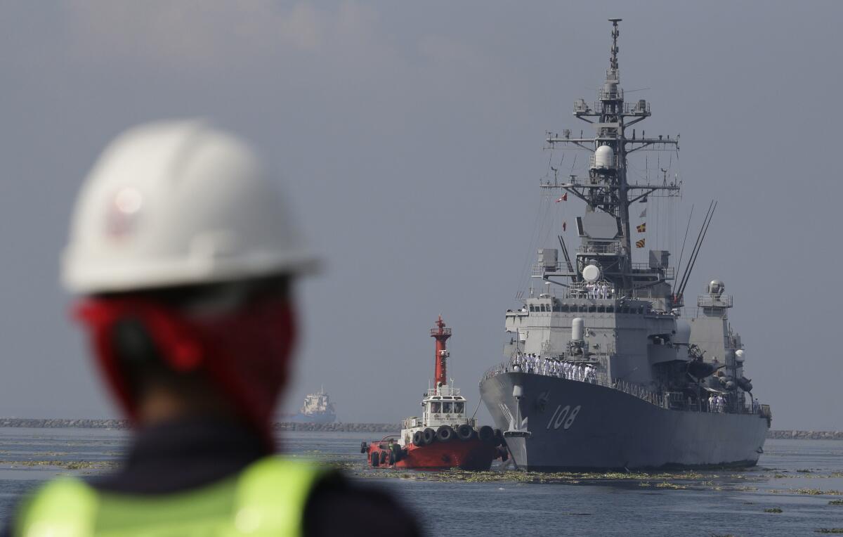 FILE - A Filipino port worker looks as the Japanese Ship Akebono (DD-108), a Murasame-class destroyer of the Japan Maritime Self-Defense Force, prepares to dock for a goodwill visit at Manila's south harbor, Philippines on Sept. 27, 2018. The United States, Japan, Australia and the Philippines will hold their first joint naval exercises, including anti-submarine warfare training, in a show of force Sunday, April 7, 2024 in the South China Sea where Beijing’s aggressive actions to assert its territorial claims have caused alarm. (AP Photo/Aaron Favila, File)