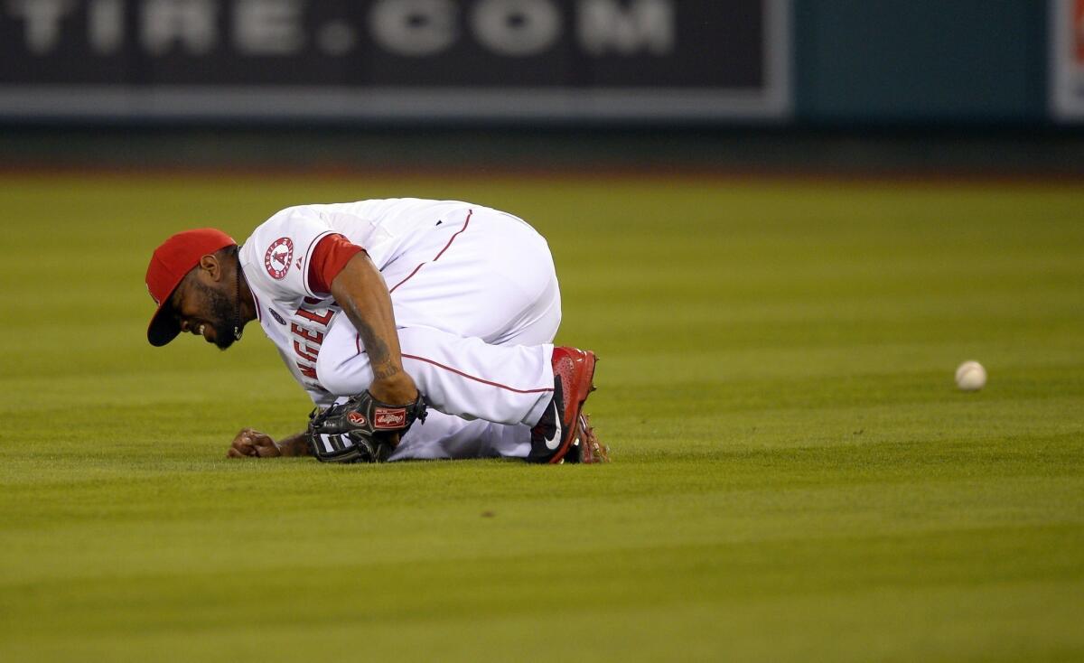 Angels second baseman Howie Kendrick writhes on the ground after making contact with right fielder Collin Cowgill while trying to make a catch in the fifth inning of the team's 5-2 loss to the Texas Rangers on Monday.