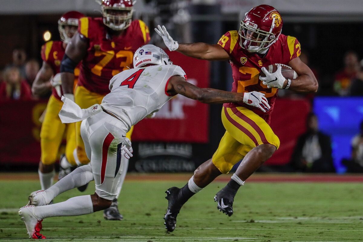 USC running back Vavae Malepeai brushes off a tackle while carrying the ball 