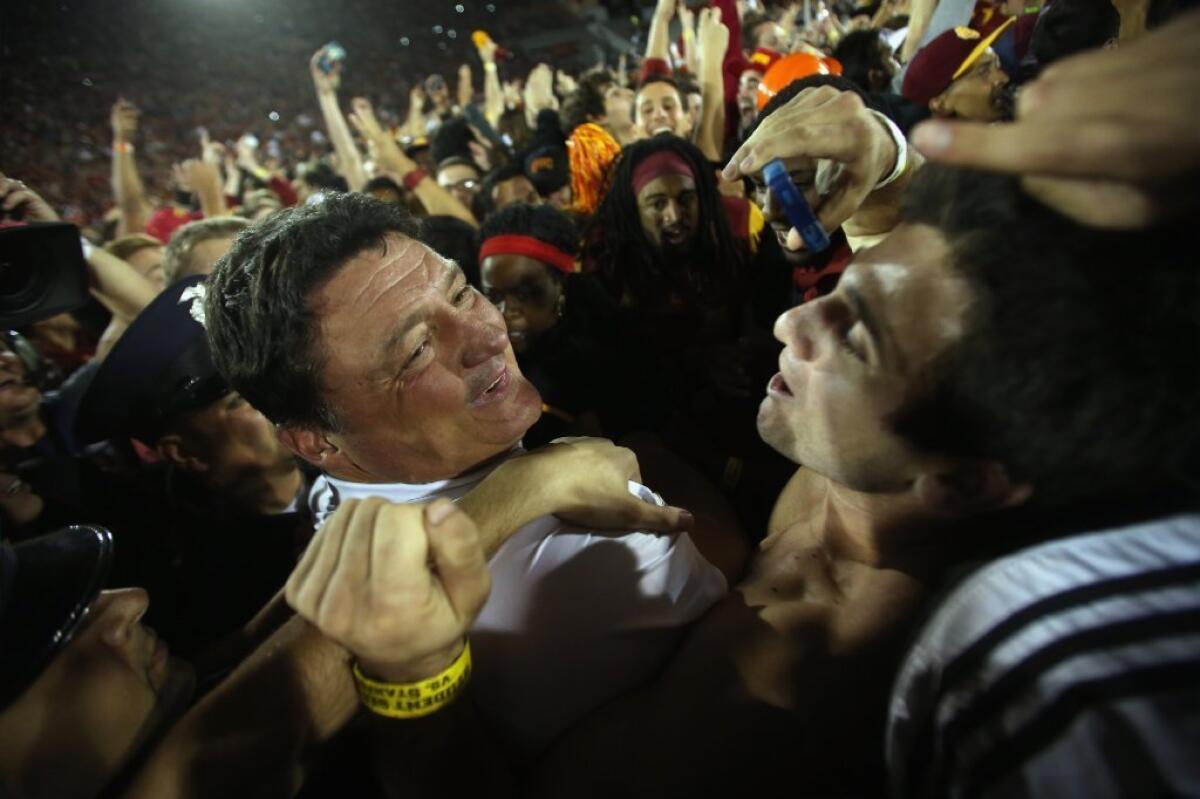 USC Trojans interim head coach Ed Orgeron celebrates the Trojans' 20-17 victory over the Stanford Cardinal as fans crowd onto the field at the Los Angeles Coliseum.