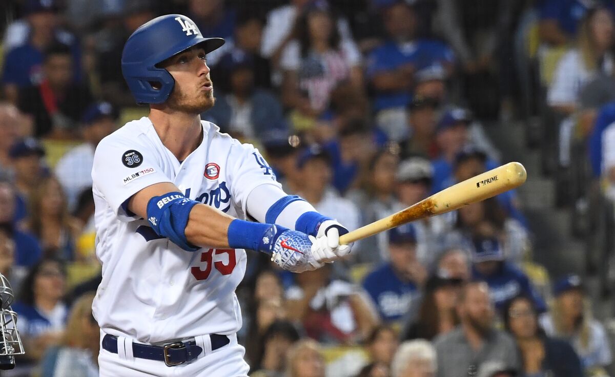 Cody Bellinger looks up, holding his bat straight out in front of him, after hitting a home run.