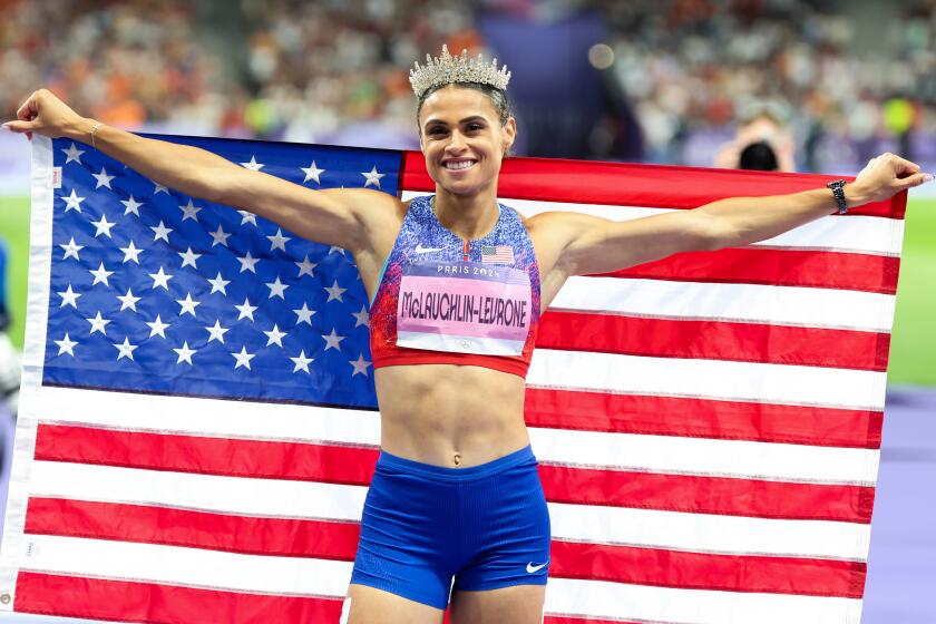 PARIS, FRANCE - AUGUST 8: Sydney McLaughlin-Levrone, of the United States, poses with a USA flag after she sets a new world record with 50.37 to win the gold medal during the womenOs 400m hurdles final in the 2024 Paris Olympics at Stade de France on Thursday, August 8, 2024 in Paris, France. (Wally Skalij / Los Angeles Times)