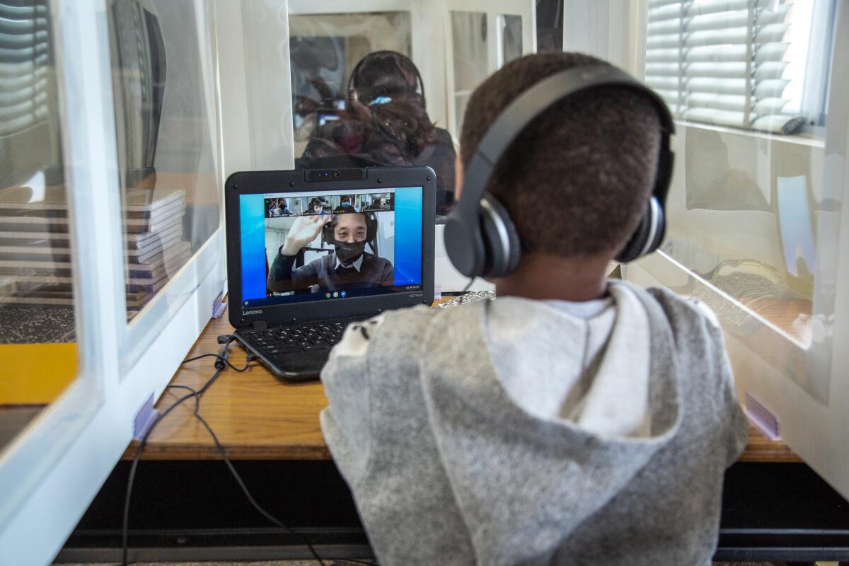 Jamarie Singleton, a third-grader at Perkins K-8, sits behind a desk partition on Monday while watching his teacher via zoom.