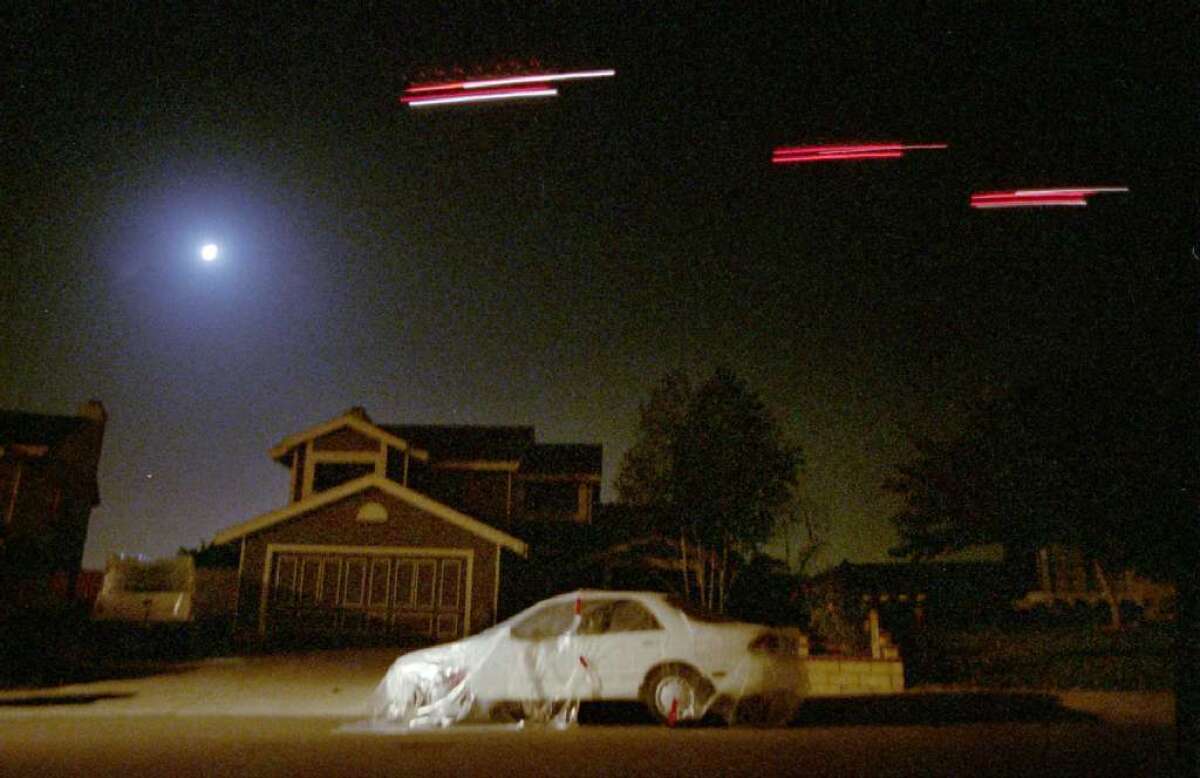 Helicopters cruise over the Camarillo neighborhood spraying malathion in 1994 to combat the first Medfly infestation in county history. Residents covered their cars with plastic tarps to avoid getting ruining the paint on their cars. (Alan Hagman / Los Angeles Times)