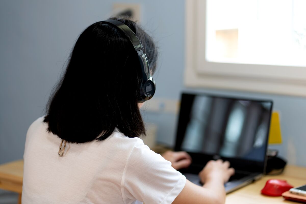 Woman with headset types on laptop computer