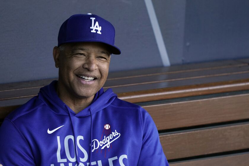 Los Angeles Dodgers manager Dave Roberts smiles in the dugout during a workout ahea.