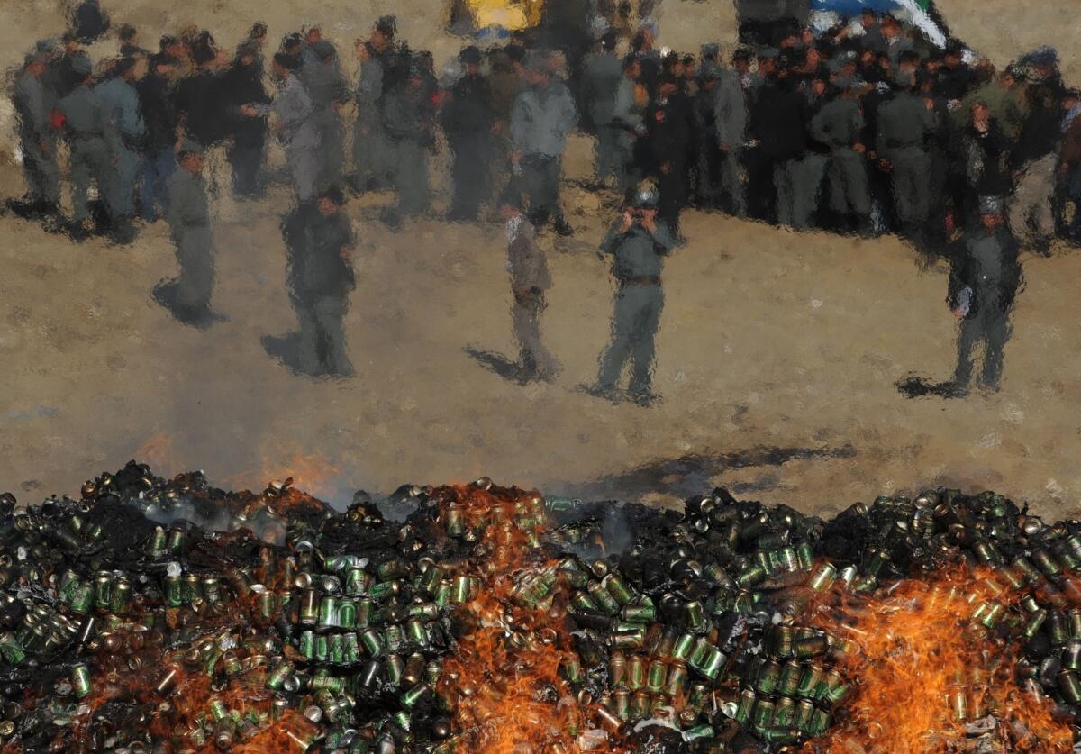 Afghan government officials and policemen watch as a cache of alcohol and drugs burns in Kabul on Tuesday.