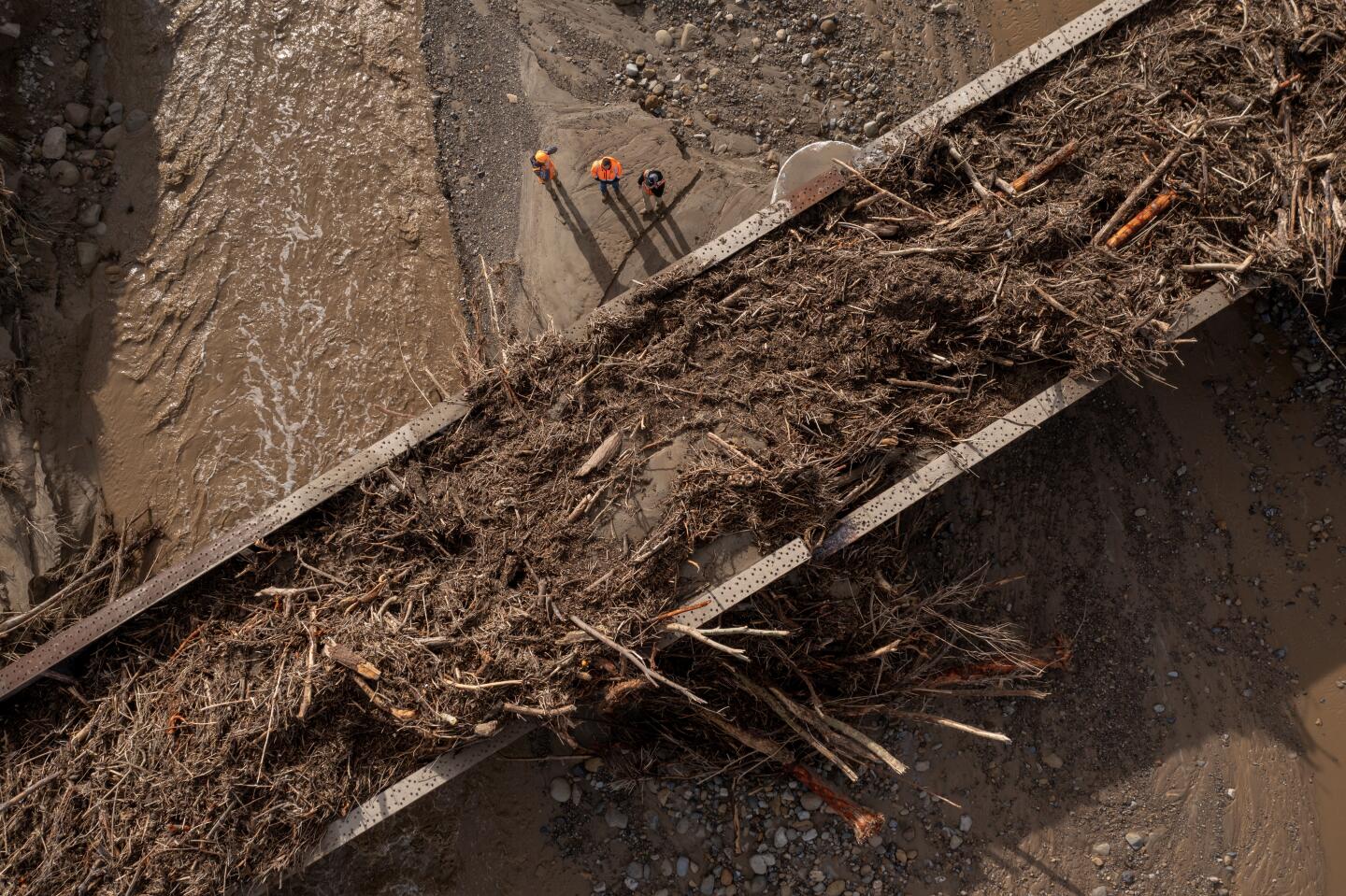 FILLMORE CA - JANUARY 11: In an aerial view, workers inspect a railway bridge over Hopper Creek that is covered in storm debris on January 11, 2023 near Fillmore, California. A series of powerful storms continue to pound California in striking contrast to the past three years of severe to extreme drought experienced by most of the state. The storms are damaging yet bringing heavy rainfall totals which, though not expected to end the drought, is helping to refill reservoirs that have shrunken to historic low levels because of drought. (Photo by David McNew/Getty Images)