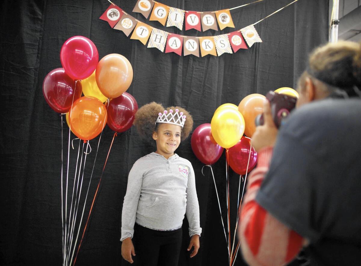 Sophia White, 7, smiles for volunteer photographer Allyson Coward, 12, at the annual Union Rescue Mission Thanksgiving dinner. White and her family are staying at the shelter; her mother recently lost her job.