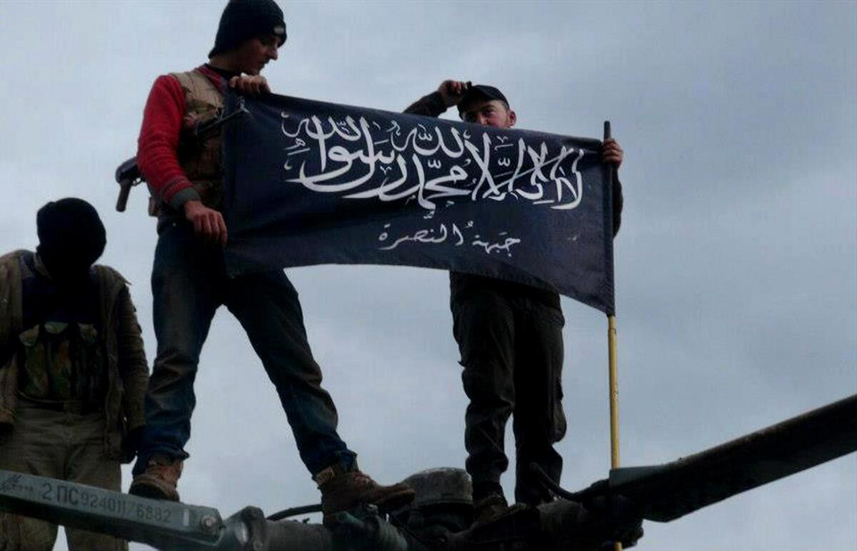 This image by a citizen journalist provided by Edlib News Network, which has been authenticated based on its contents and other Associated Press reporting, shows rebels from Al Qaeda-affiliated Al Nusra Front waving their brigade flag on the top of a Syrian air force helicopter captured by the rebels, in Idlib province, northern Syria.