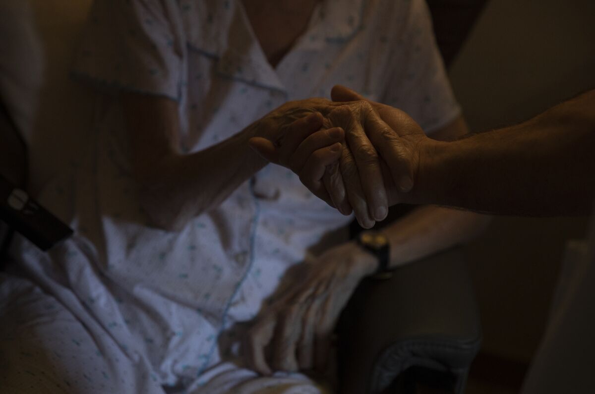 A healthcare worker holds the hand of a resident at the CHC nursing home in Landenne, Belgium, Wednesday, Nov. 4, 2020. Belgium, proportionally still the worst-hit nation in Europe when it comes to coronavirus cases, said Wednesday that there were increasing signs of that a turning point in the crisis was drawing close. The Belgian Army has been deployed to help several hard hit areas in the country including nursing homes. (AP Photo/Virginia Mayo)
