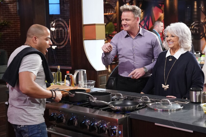 A contestant, left, cooks for Gordon Ramsay and Paula Dean on "MasterChef." 