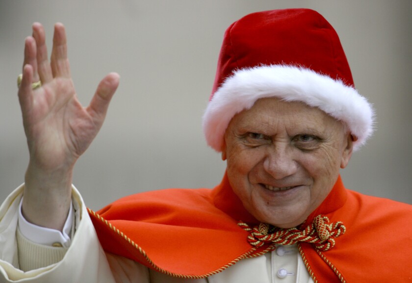 Pope Benedict XVI, sporting a fur-trimmed hat in the rich red color of a Santa hat, waves to pilgrims upon his arrival in St. Peter's Square at the Vatican. The red hat with white fur trimming is known in Italian as the "camauro."