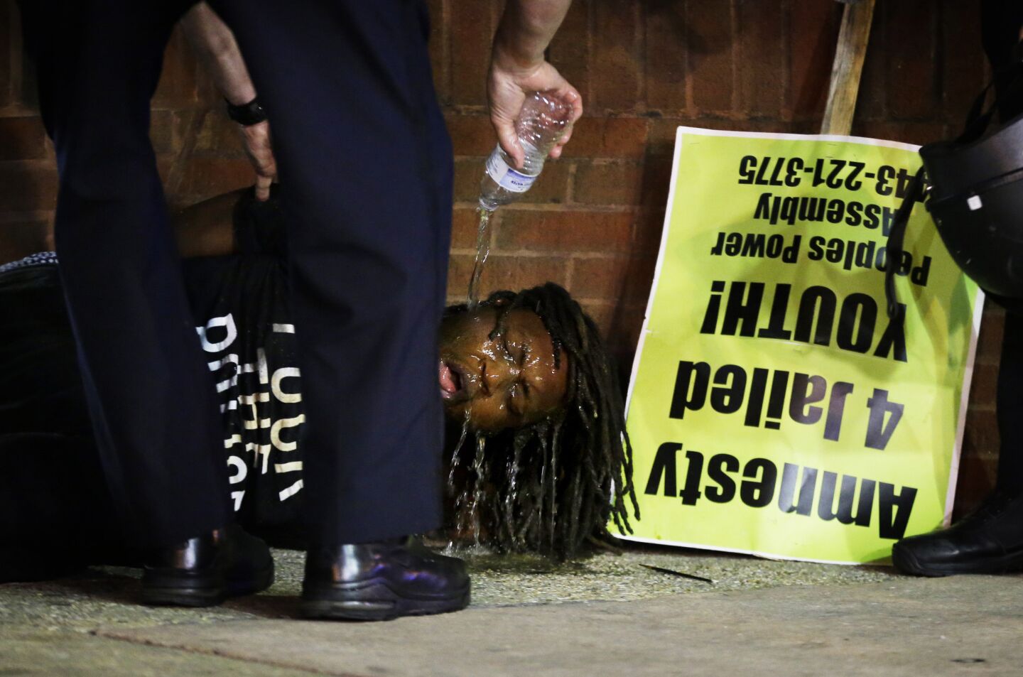 Police pour water over the face of a man after he was arrested and hit with pepper spray as police enforced a 10 p.m. curfew Saturday in Baltimore.