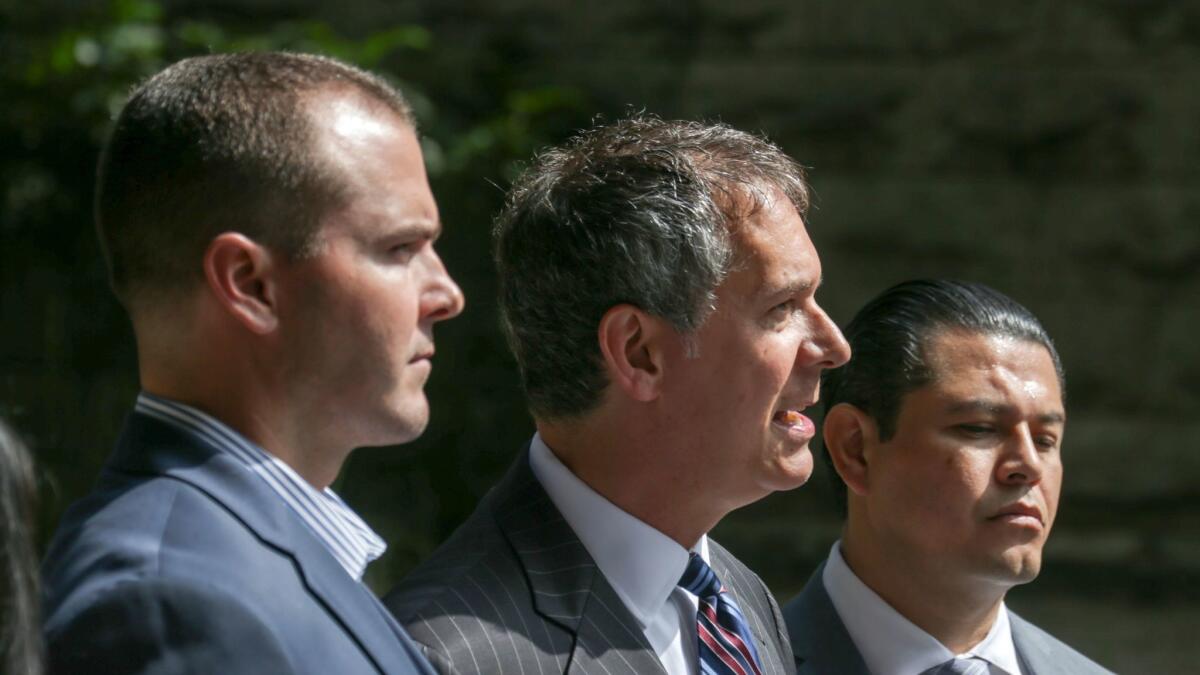 Attorney Ron Kaye, flanked by Los Angeles County sheriff's deputies Robert Lindsey, left, and Charles Rodriguez, holds a news conference outside the Clara Shortridge Foltz Criminal Justice Center in downtown Los Angeles.
