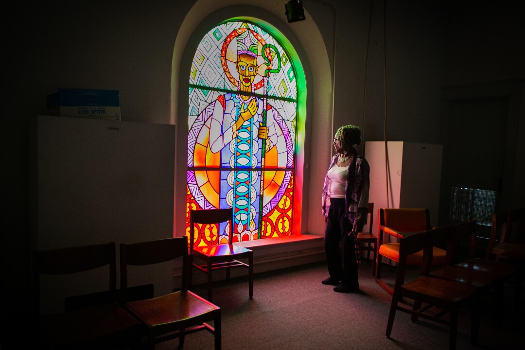 A woman looks at a stained glass window