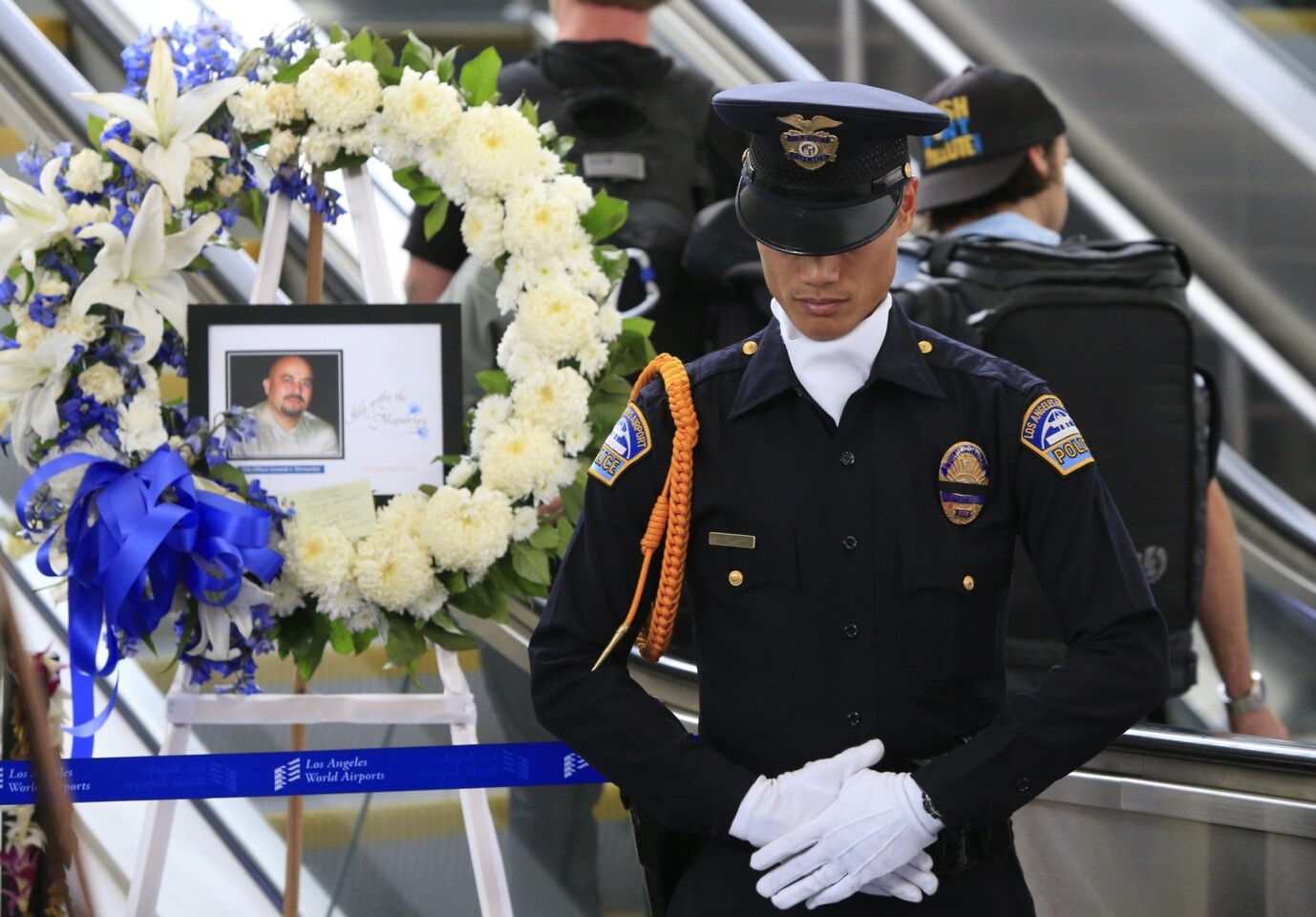 Los Angeles Airport Police Department Officer Fritz Corros stands in silence as an honor guard at the makeshift memorial to fallen TSA Officer Gerardo Hernandez.