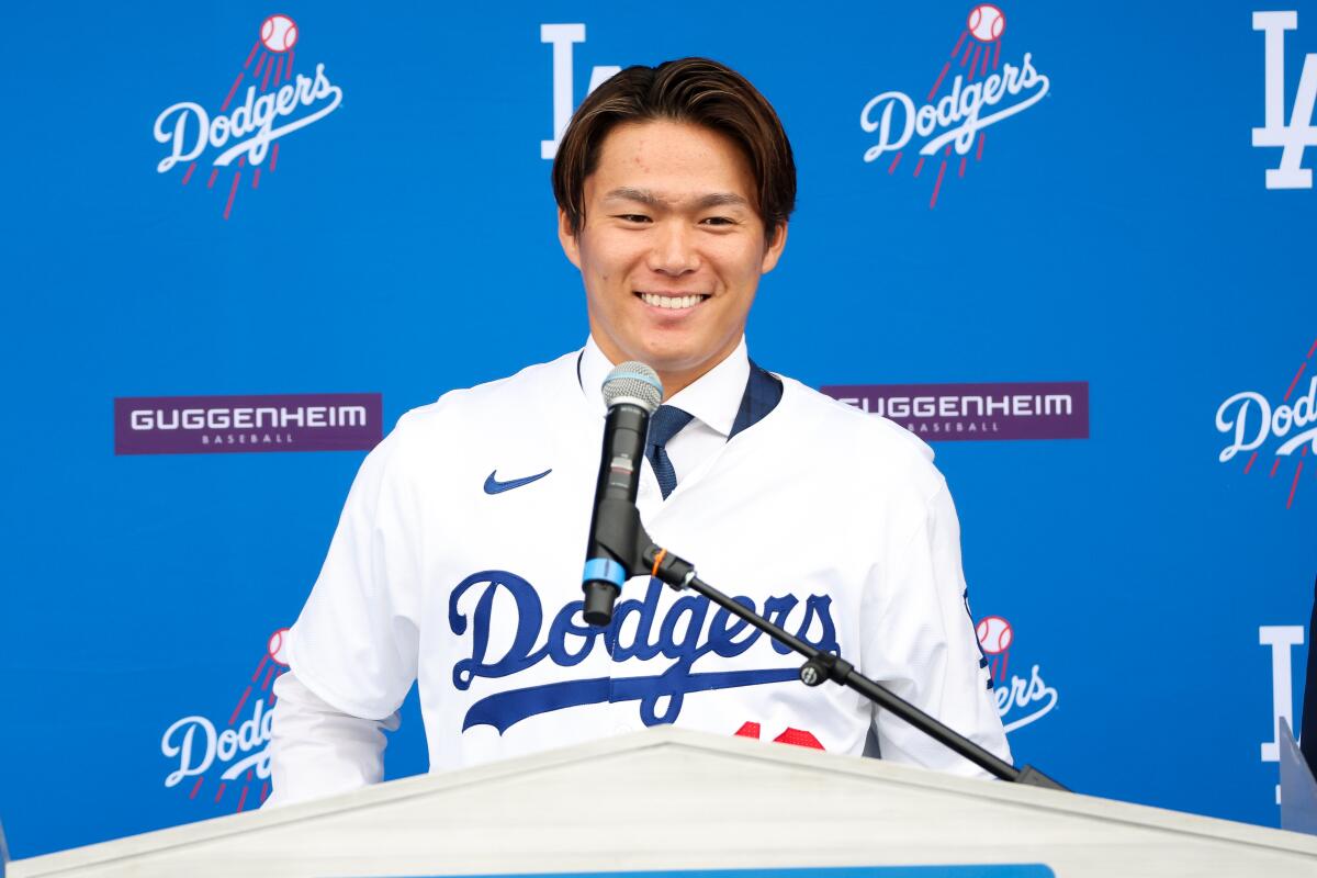Yoshinobu Yamamoto smiles at a Dodgers news conference.