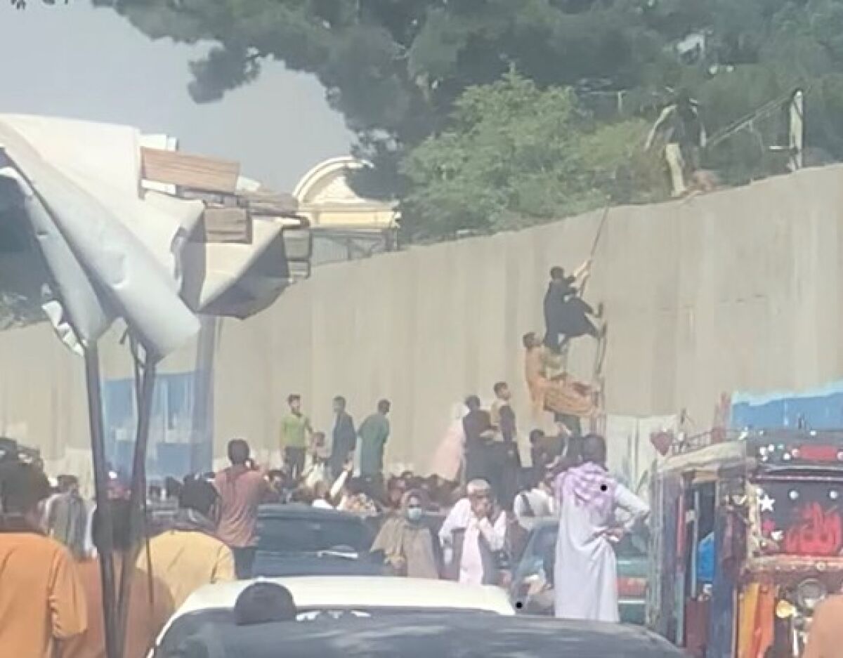 People trying to escape over the wall, leading to the Karzai International Airport in Kabul, Afghanistan.