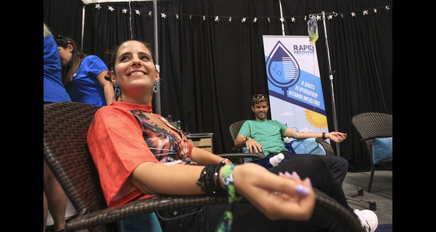 Spencer Berman, left, who is taking an IV containing vitamin mixture for energy called "Give it to Me Straight Up" which costs $100, as Alex Johnson takes an IV called "Festival Fatigue Fighter", costing between $140 and $160, at the Rapid Recovery booth.