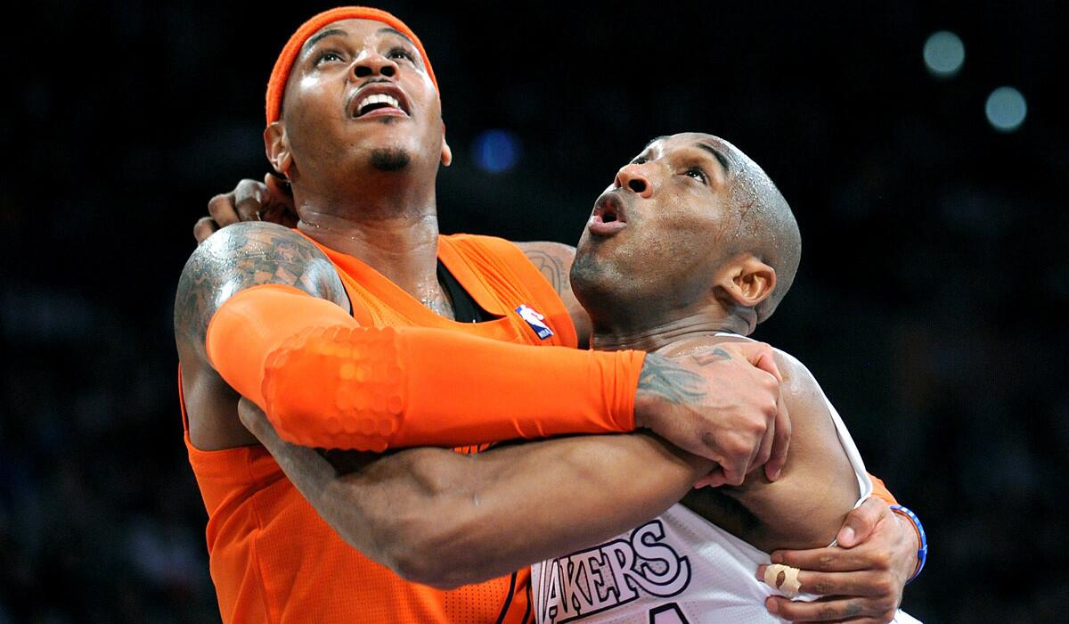 Carmelo Anthony, then with the New York Knicks, and Kobe Bryant jump with their arms around each other as they fight for position in a 2014 game.