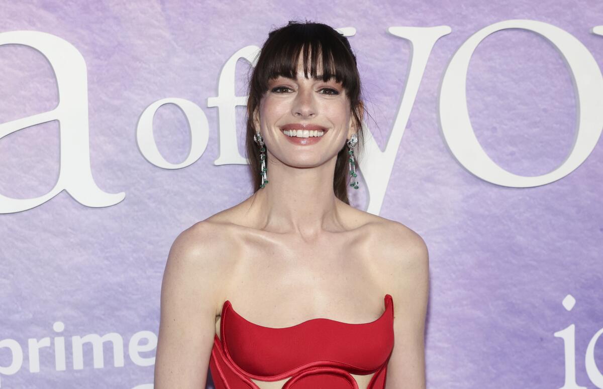 Anne Hathaway smiling in a strapless red gown