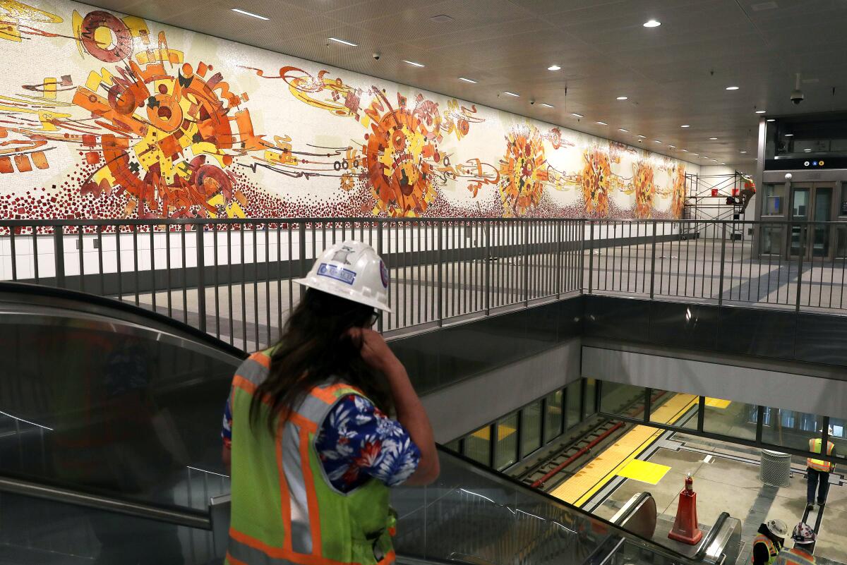 A mosaic mural featuring cosmic patterns in red, orange and yellow occupies an entire wall in a level of a Metro station