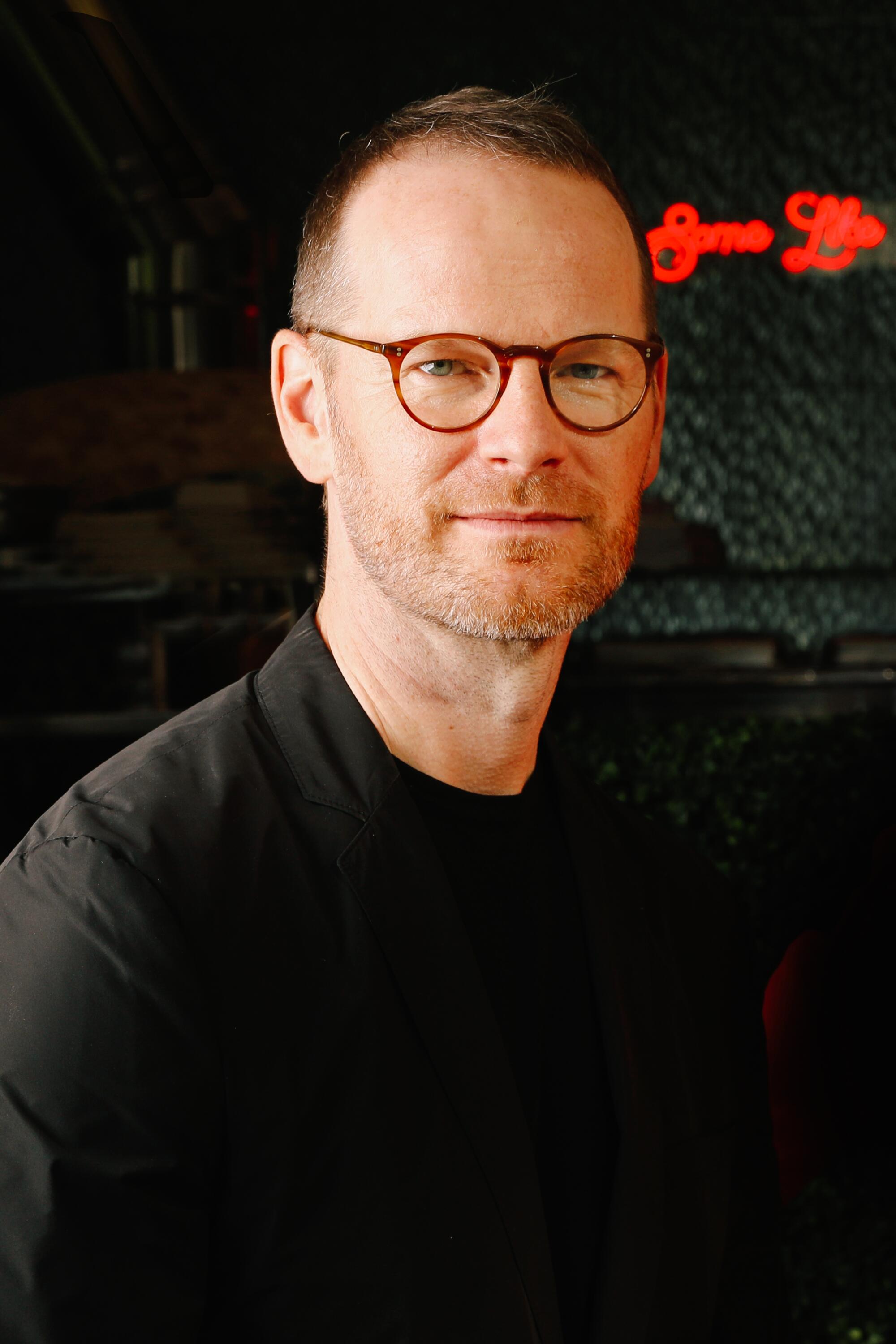 Filmmaker Joachim Trier, wearing glasses and a black shirt.