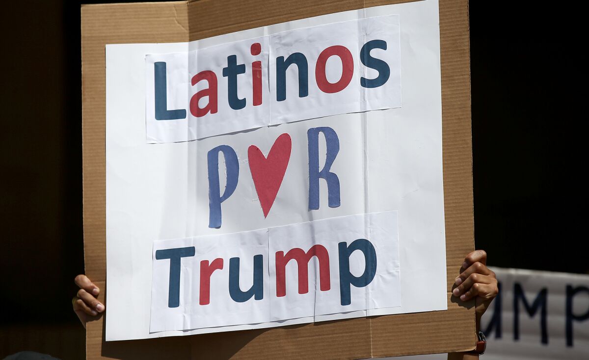 A man hoists a sign during a rally of about 100 of Donald Trump's Latino supporters outside Anaheim City Hall on Aug. 28, 2016.