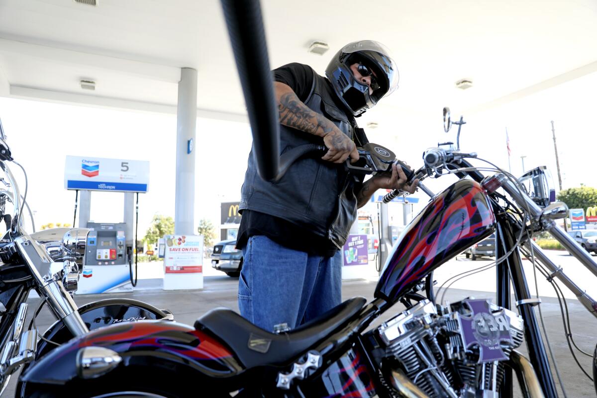 Mike Delgado pumps gas into his 2007 Swift 124 motorcycle at the Chevron gas station in Orange.