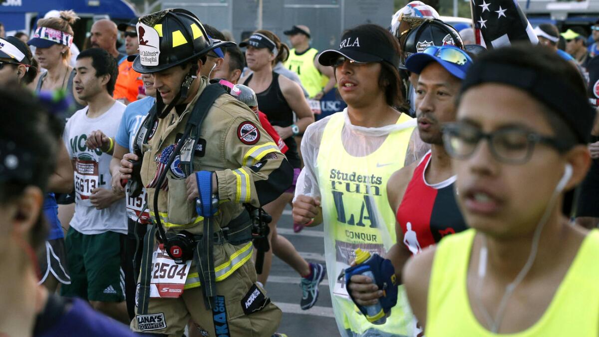 A man wearing firefighter gear crosses the starting line at Dodger Stadium.