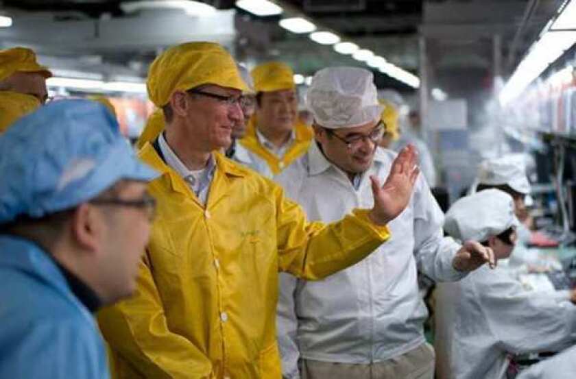 Apple Chief Executive Tim Cook, center left, visits the iPhone production line at the newly built Foxconn manufacturing facility at Zhengzhou Technology Park in China. Many of Apple's production lines in the country have gone quiet amid measures to contain the spread of coronavirus.