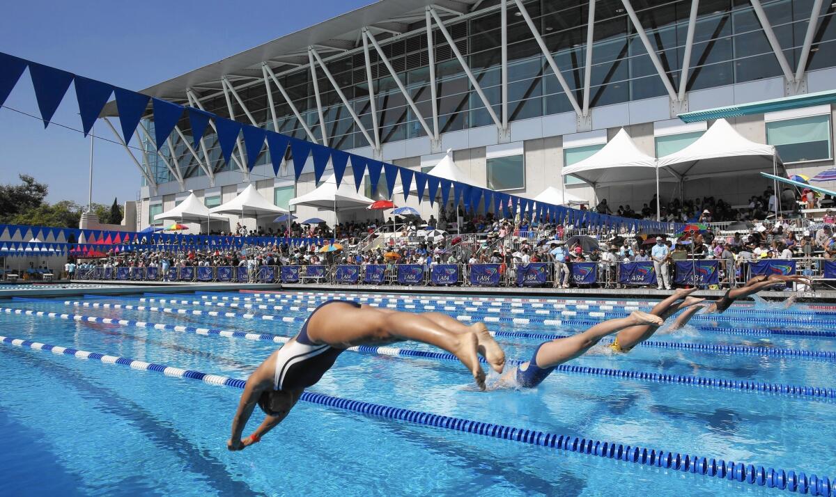 Swimmers dive in for a race at an event at the John C. Argue Swim Stadium put on by the LA84 Foundation's aquatics program.
