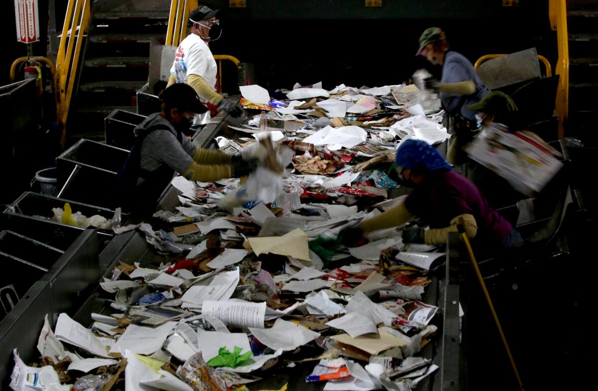 Workers sort through waste inside the cavernous Athens material recovery facility in Sun Valley on Dec. 28, 2023.