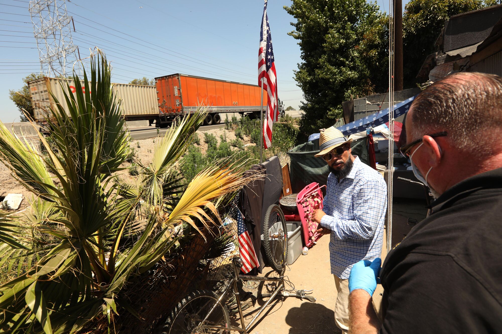 Outreach worker John Oliver, right, talks with Carlos Aguirre, who lives in an encampment along the 710 Freeway.