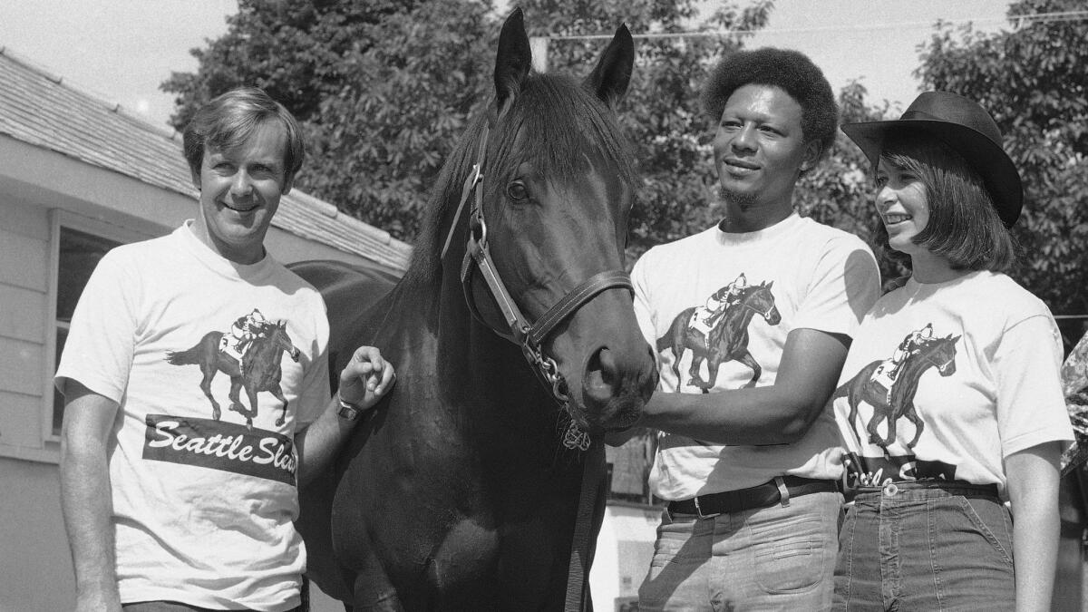 Seattle Slew stands with owners Mickey, left, and Karen Taylor and groom John Preston at the Belmont stables on June 12, 1977.