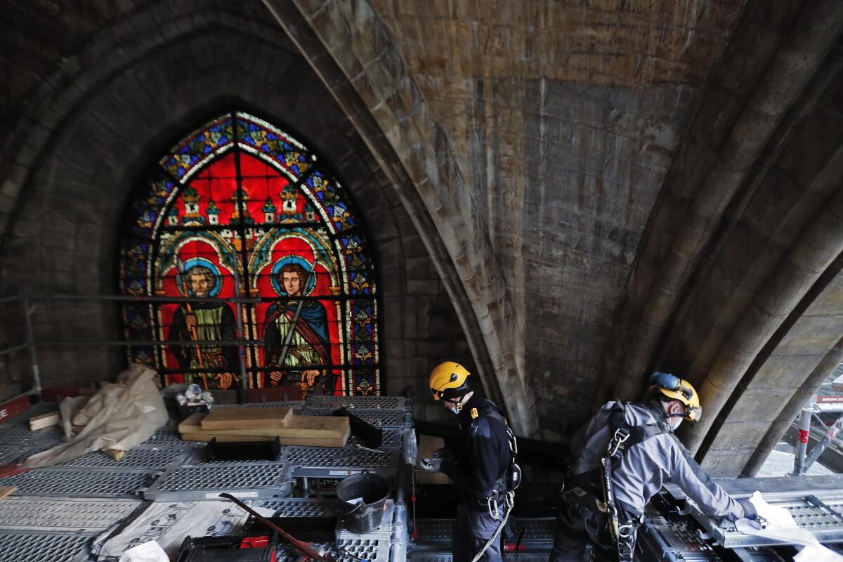 Workers near a stained glass window under the vaults at the reconstruction site of the Notre Dame Cathedral
