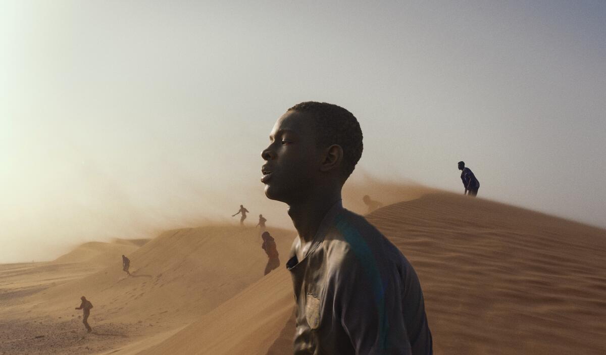A teenager walks through a desert.