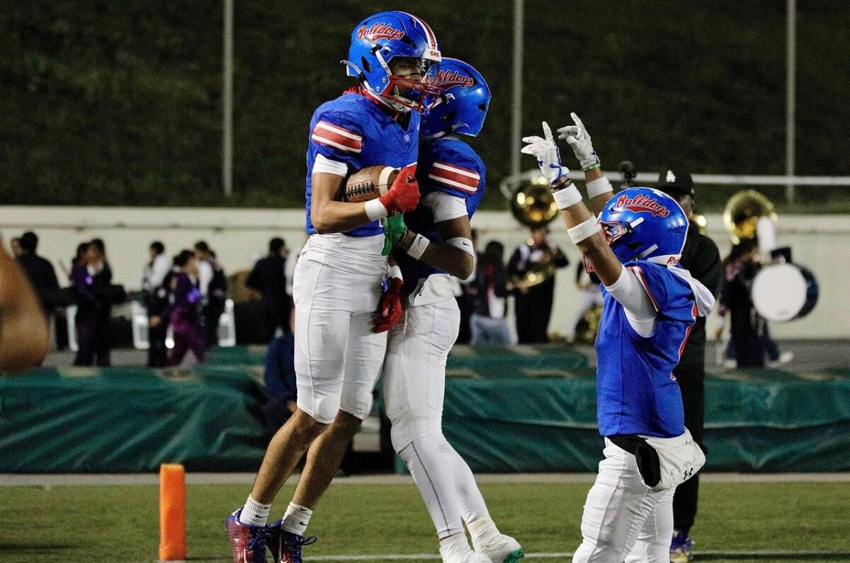 Garfield receiver Jayden Barnes leaps in the air holding the football to celebrate a touchdown catch with teammates.