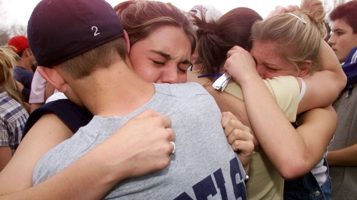Students hug each other in the parking lot outside Columbine High School in Littleton, CO, the day after the infamous school shooting on April 20, 1999.