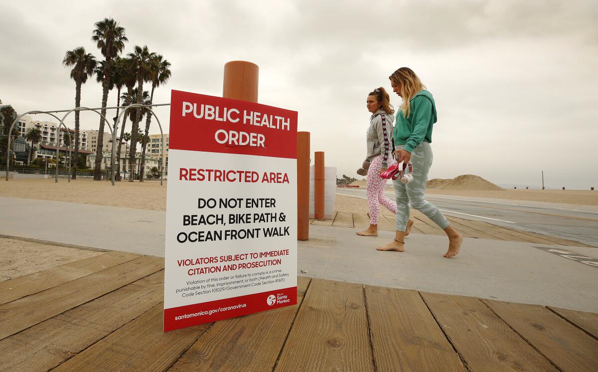 Kim Abt, left, and Rachel Portugal walk the beach after a social media workout Tuesday morning in Santa Monica.  