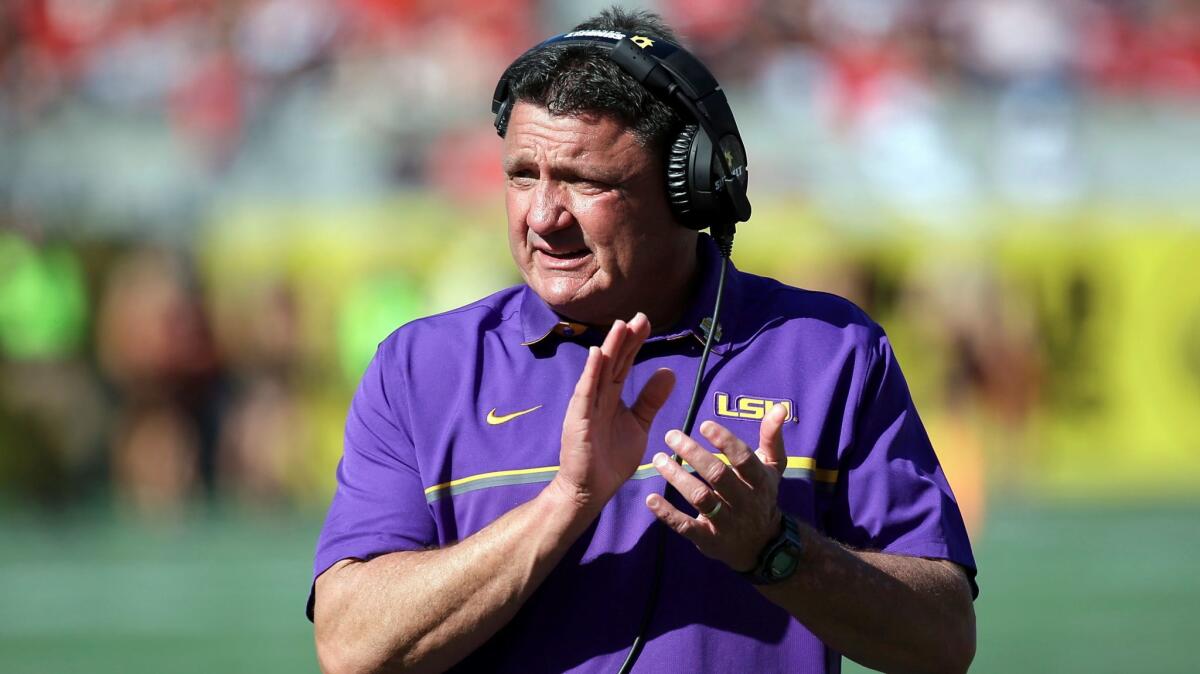 LSU coach Ed Orgeron claps while standing on the sideline.