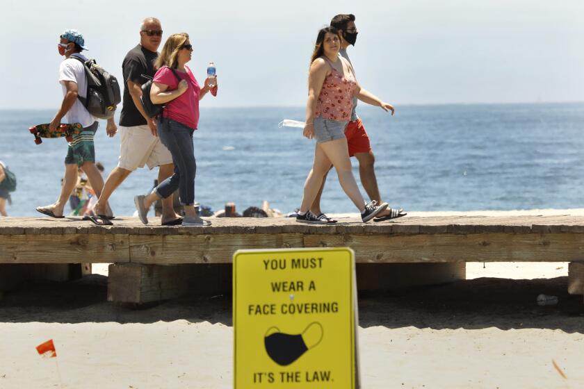 LAGUNA BEACH, CALIFORNIA-JULY 31, 2020-In Laguna Beach, California, signs are posted that read "You must wear a face covering. It's the law," but not everyone is obeying. (Carolyn Cole/Los Angeles Times)