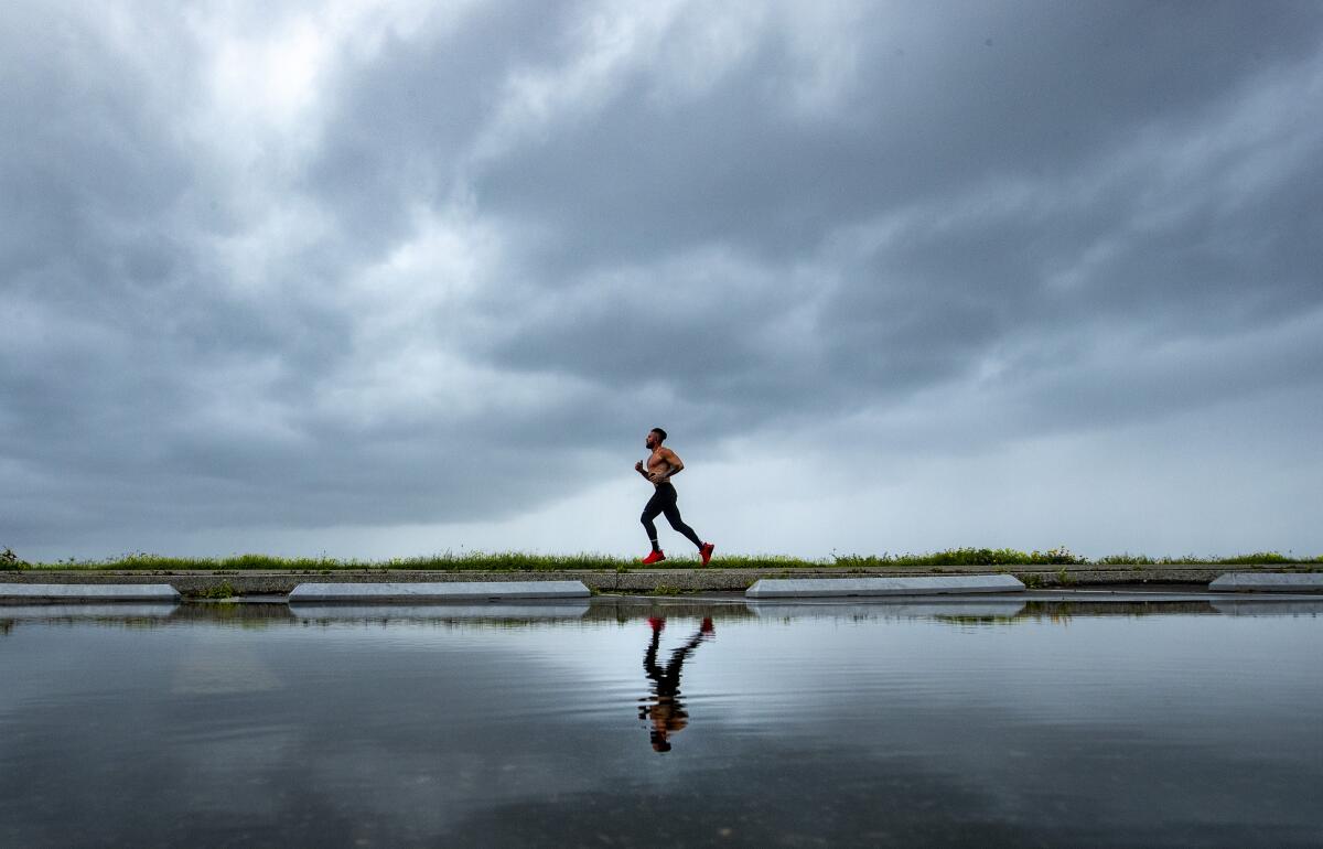 A jogger runs along the path at Will Rogers State Beach as storm clouds move onshore in Pacific Palisades earlier this month. 