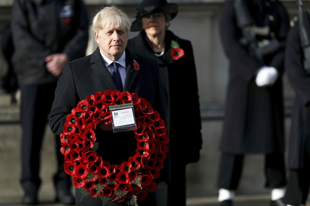 FILE - Britian's Prime Minister Boris Johnson carries a wreath, during the Remembrance Sunday service at the Cenotaph, in Whitehall, London, Sunday Nov. 8, 2020. Johnson says Britain and the United States will work together to support democracy and combat climate change. He denies that his close ties to President Donald Trump would hurt U.K.-U.S relations once President-elect Joe Biden takes office in January. (Peter Nicholls/Pool Photo via AP, File)
