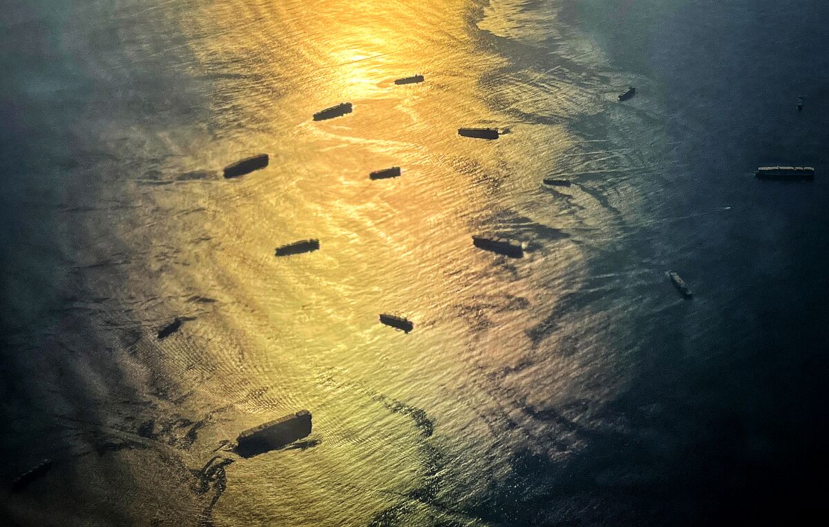 An aerial view of container ships waiting at sea.