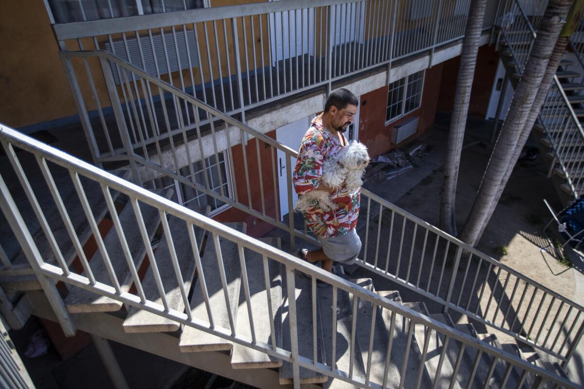 Mario Blanco walks down the steps at the hotel in Downey where he had been living under Project Roomkey. 