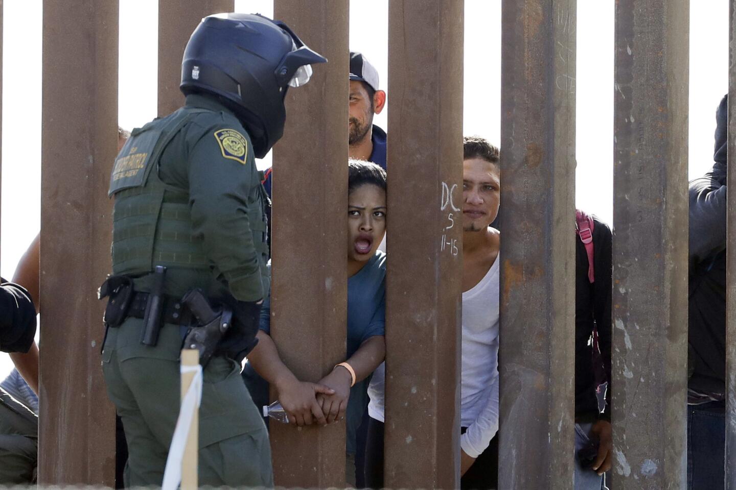 Migrants from Central America yell through a border fence between San Diego and Tijuana at a U.S. Customs and Border Patrol agent after he pulled down a banner on Nov. 25, 2018.