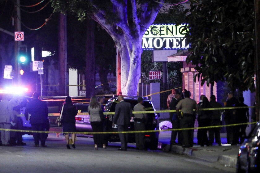 Police and other law enforcement at a cordoned-off crime scene in front of a motel